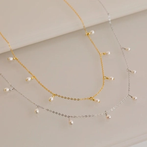 Detail of minimalist gold and silver stainless steel pearl necklaces with delicate chains