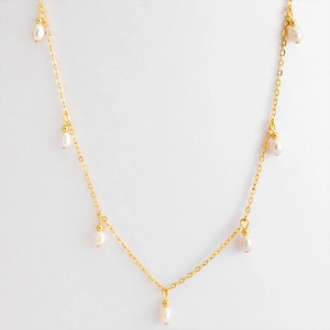 Detailed view of gold chain necklace with five oval white pearls on white background