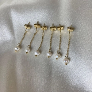 Detailed view of three pairs of gold-plated stainless steel chain earrings with white pearls