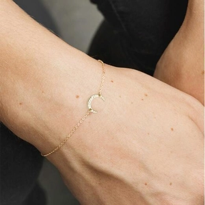 Macro detail of gold-plated crescent moon bracelet with unique hammered texture finish