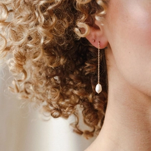 Elegant gold chain earrings with white pearls shown on model in a minimalist style