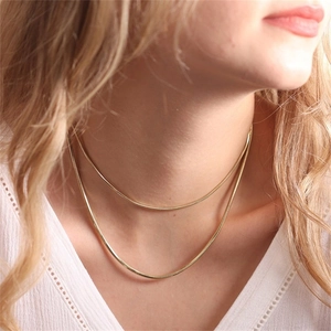 Zweilagige goldene Schlangenkette aus Titanstahl, präsentiert an einem weiblichen Model