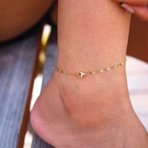 Detail of a minimalist gold-plated stainless steel sequin chain anklet on a model