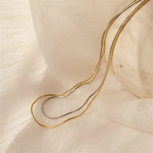 Details von Schlangenketten aus Edelstahl in Gold und Silber auf einer Steinoberfläche