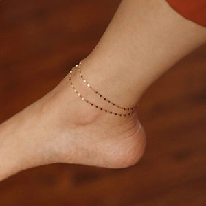 Detail of a double-layered rose gold anklet with tiny sequins on a model's ankle