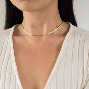 Detailopname van een elegante gouden slangenketting gedragen op het sleutelbeen