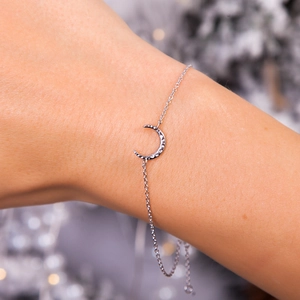 Macro view of silver crescent moon bracelet with hammered texture on a female wrist