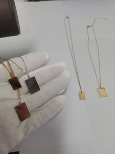 Vue détaillée de colliers pendentifs rectangulaires minimalistes en or, argent et cuivre