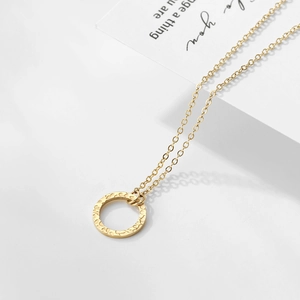 Macro view of gold-plated geometric round pendant with unique hammered texture on chain
