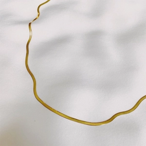 Gedetailleerde opname van gouden haringgraat ketting op elegante witte satijnen stof