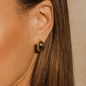 Gros plan d'une boucle d'oreille goutte en plaqué or sur un mannequin au style moderne