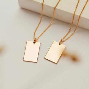 Détail macro de pendentifs rectangulaires dorés minimalistes avec une finition miroir lisse