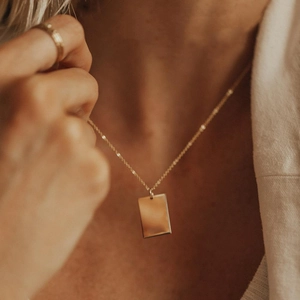 Vue rapprochée d'un collier doré avec pendentif rectangulaire sur un mannequin