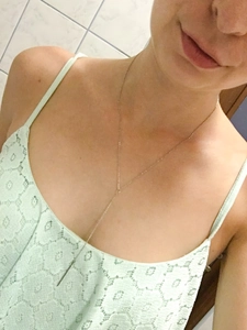 Gros plan d'un collier en Y plaqué or en acier inoxydable porté par un mannequin femme