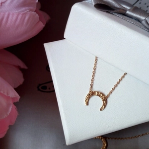 Close-up of golden crescent moon bracelet with hammered texture on white jewelry box
