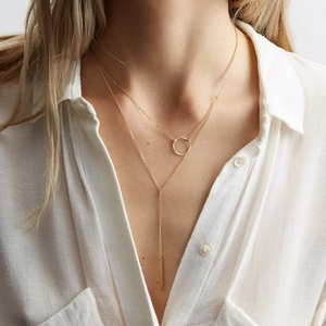 Détail d'un collier en Y doré à deux rangs avec pendentifs cercle et barre sur mannequin