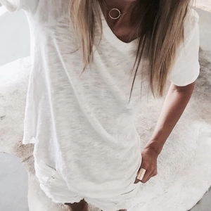 Close-up of the natural linen texture and V-neck detail of this minimalist white summer T-shirt