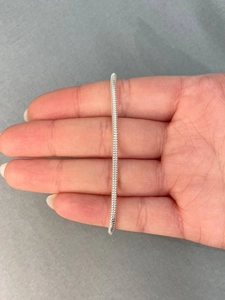 Gedetailleerd beeld van een zilveren slangenketting armband aan de hand met textuur