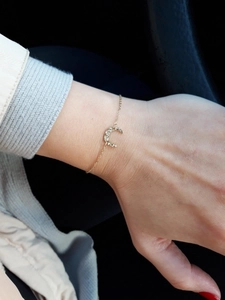 Detailed close-up of a gold-plated moon bracelet with pave-set crystals on a woman's wrist