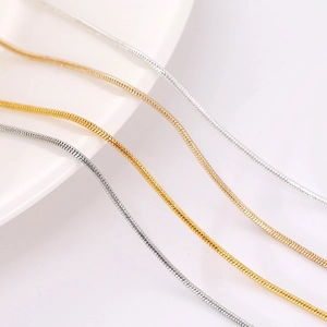 Detail van goud, roségoud en zilveren slangenketting armbanden op wit keramiek bord
