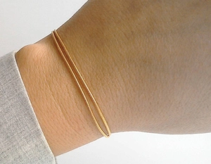 Macro-opname van een minimalistische dubbellaagse gouden slangenketting armband
