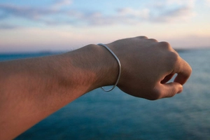 Detail van een minimalistische zilveren slangenkettingarmband om de pols op het strand