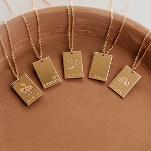 Gros plan détaillé de cinq colliers à pendentif rectangulaire dorés avec gravures