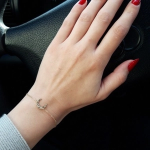 Minimalist gold moon bracelet with sparkling rhinestones worn on a female wrist