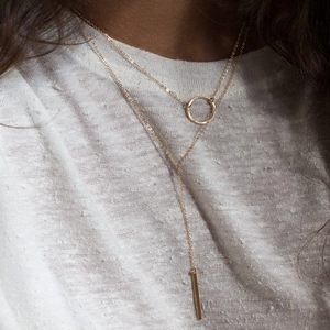 Détail du collier Y doré multicouche avec pendentif rond et barre verticale sur mannequin