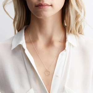 Collier doré avec pendentif circulaire martelé porté par un mannequin femme