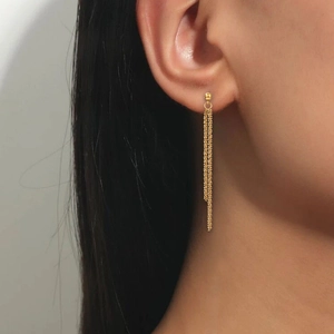 Close-up of long gold stainless steel tassel earrings on model with chain drop detail
