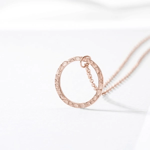 Détail du collier avec pendentif cercle en or rose présentant une texture martelée chic
