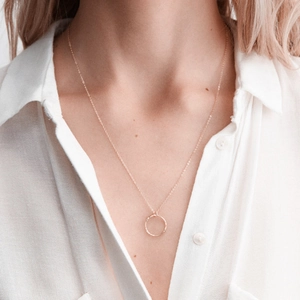 Collier minimaliste à pendentif anneau doré martelé porté par un mannequin