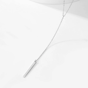 Détail macro d'un collier en Y minimaliste en acier inoxydable avec un long pendentif vertical