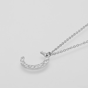 Macro shot of silver crescent moon pendant with hammered texture on fine chain