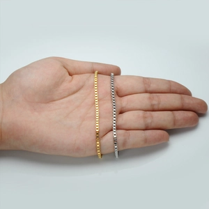 Macro detail of minimalist gold and silver stainless steel box chains on hand