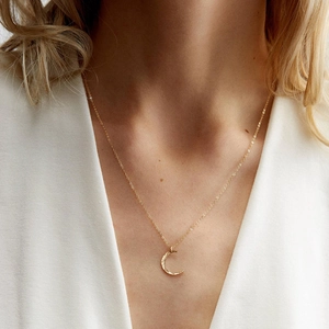 Close-up of golden crescent moon necklace with hammered texture on a model neck