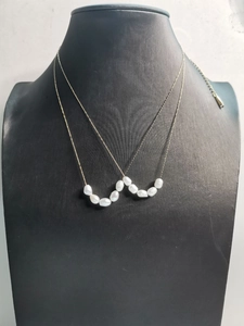 Detail view of double layered golden stainless steel necklaces with baroque pearls on bust