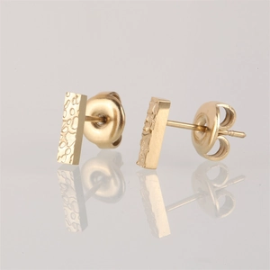 Macro shot of gold hammered rectangular stud earrings with unique textured finish