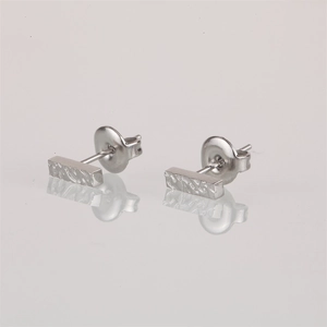 Macro shot of silver geometric bar earrings with textured hammered finish and butterfly backs