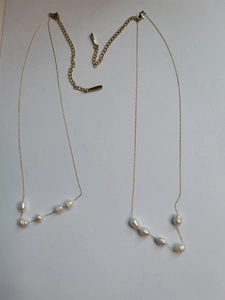 Detail of golden stainless steel necklace with white baroque pearls and lobster clasp