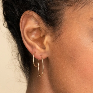 Doubles créoles minimalistes en acier inoxydable doré portées par un mannequin femme