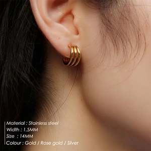 Close-up of three-row gold C-shaped stainless steel earrings worn on earlobe