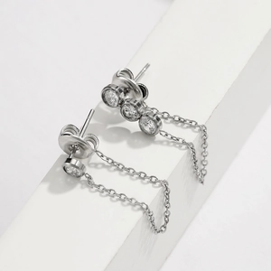 Detailed macro view of silver steel earrings featuring cubic zirconia and elegant chains