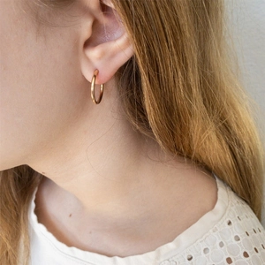 Elegant gold plated stainless steel hoop earrings worn by a model in a minimal style