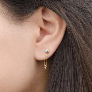 Elegant gold chain fringe earring with sparkling zircon stud shown on model's ear