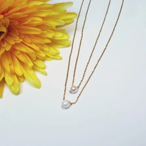 Detailansicht von zwei minimalistischen Edelstahl-Halsketten mit eleganten Perlenanhängern
