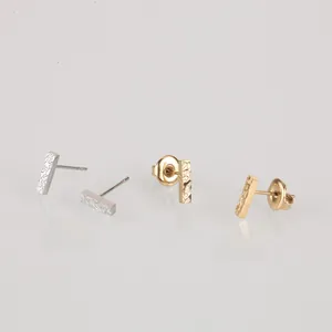 Detail of minimalist bar stud earrings with textured lava finish in gold and silver