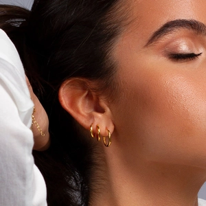 Close-up of model wearing three graduated gold plated stainless steel hoop earrings