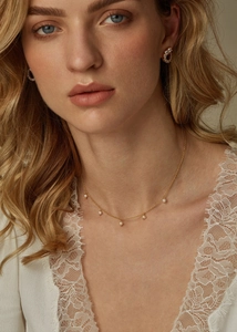 Detail of a gold choker necklace with five pearls worn by a model with lace collar